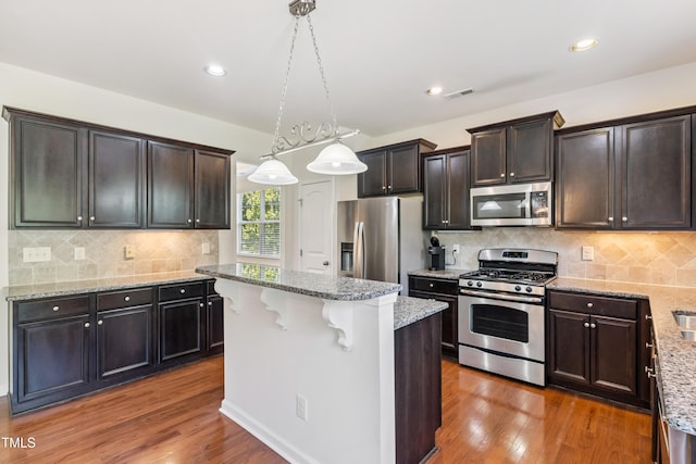 4 Seawell Ct, Durham, NC 27703 - kitchen with stainless steel appliances, dark wood finished floors, light stone counters, a center island, and recessed lighting
