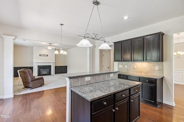 4 Seawell Ct, Durham, NC 27703 - kitchen with a ceiling fan, a glass covered fireplace, backsplash, dark wood-style flooring, and light stone countertops
