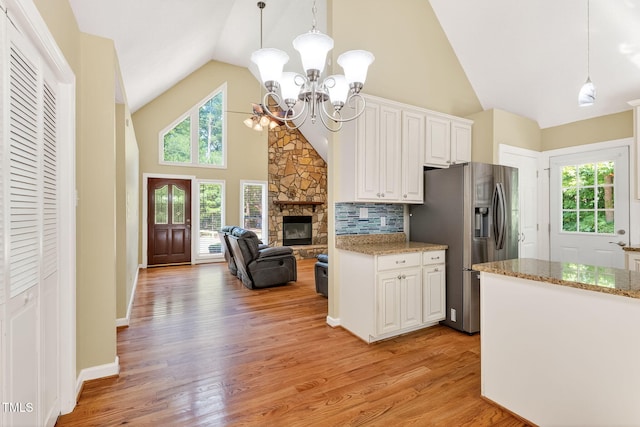 116 Seminole Dr, Louisburg, NC 27549 - kitchen with stainless steel fridge, high vaulted ceiling, a chandelier, white cabinetry, and light wood-type flooring