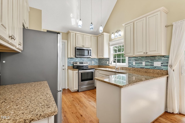 116 Seminole Dr, Louisburg, NC 27549 - kitchen with appliances with stainless steel finishes, a peninsula, backsplash, lofted ceiling, and light wood-type flooring