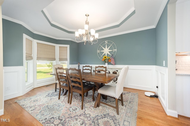 141 Vibernum Vw, Four Oaks, NC 27524 - dining area with a chandelier, a tray ceiling, light wood-style flooring, a wainscoted wall, and ornamental molding