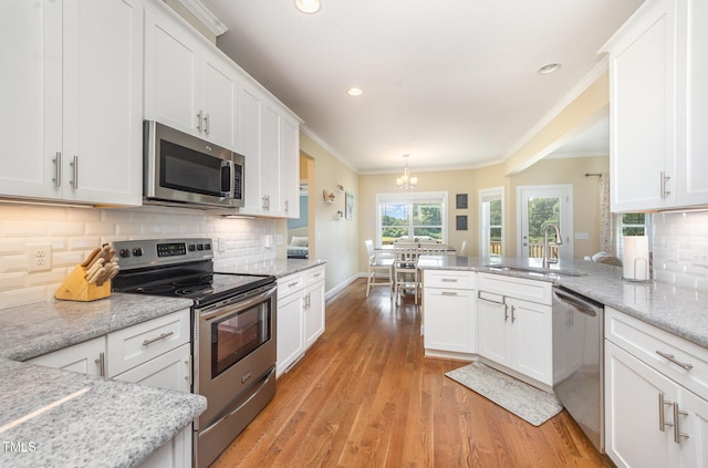 141 Vibernum Vw, Four Oaks, NC 27524 - kitchen with appliances with stainless steel finishes, white cabinets, a chandelier, light wood-style floors, and crown molding