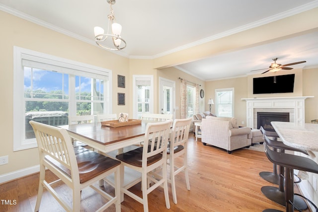 141 Vibernum Vw, Four Oaks, NC 27524 - dining room with crown molding, light wood-type flooring, a ceiling fan, a glass covered fireplace, and a chandelier