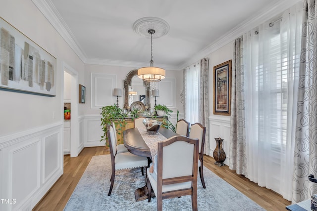 126 Gwendolyn Way, Fuquay Varina, NC 27526 - dining area with a chandelier, a decorative wall, crown molding, light wood-type flooring, and a wainscoted wall