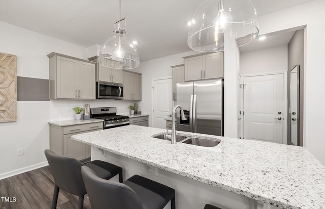 1001 Jensen Rd, Durham, NC 27703 - kitchen featuring appliances with stainless steel finishes, gray cabinets, dark wood-style flooring, a kitchen breakfast bar, and decorative backsplash