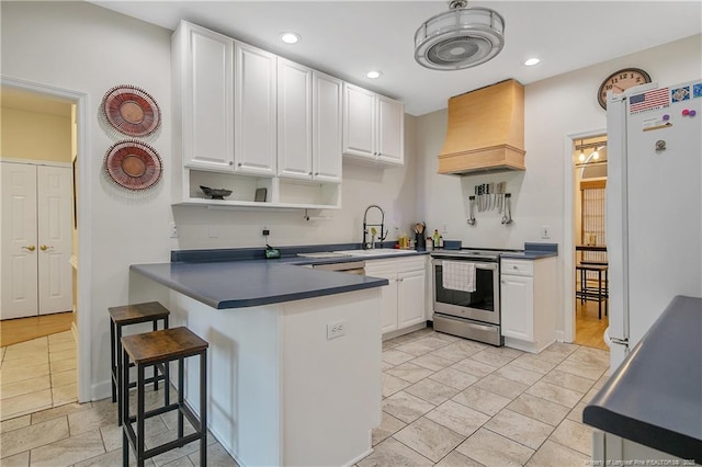 7655 Lucinda Ln, Linden, NC 28356 - kitchen featuring stainless steel range with electric stovetop, custom exhaust hood, dark countertops, white cabinetry, and recessed lighting