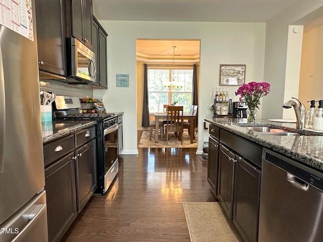 505 Poplar St, Durham, NC 27703 - kitchen featuring stainless steel appliances, dark stone counters, dark wood-style flooring, a chandelier, and dark brown cabinetry