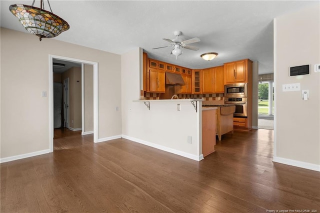 116 Bledsoe St, Hope Mills, NC 28348 - kitchen with appliances with stainless steel finishes, a peninsula, a kitchen bar, brown cabinetry, and glass insert cabinets