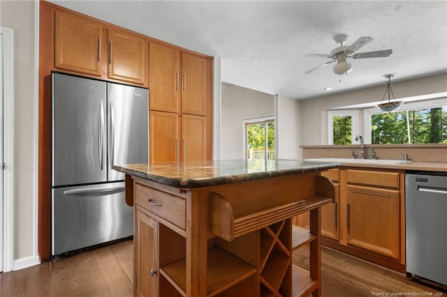 116 Bledsoe St, Hope Mills, NC 28348 - kitchen with appliances with stainless steel finishes, dark wood-type flooring, brown cabinetry, a ceiling fan, and pendant lighting