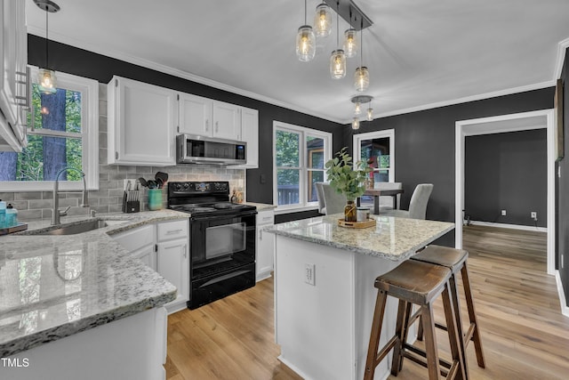 350 Amherst Creek Dr, Wake Forest, NC 27587 - kitchen featuring black range with electric cooktop, stainless steel microwave, white cabinetry, decorative backsplash, and a breakfast bar