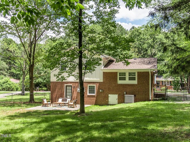 3009 Omah St, Durham, NC 27705 - back of house featuring brick siding, a patio, a shingled roof, an outdoor hangout area, and board and batten siding