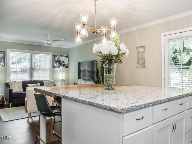 3009 Omah St, Durham, NC 27705 - kitchen featuring open floor plan, crown molding, white cabinets, a center island, and light stone countertops