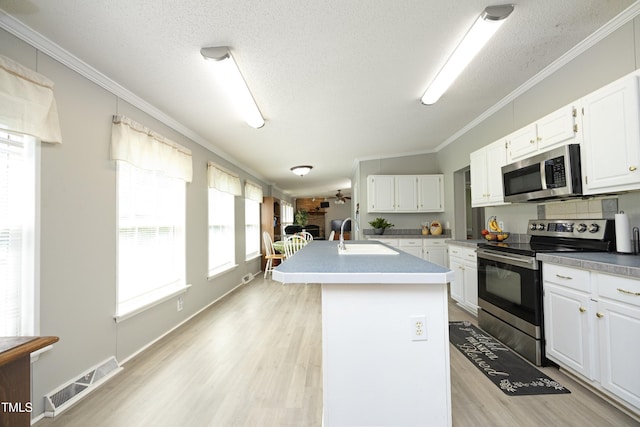 205 N Raleigh Farms Rd, Youngsville, NC 27596 - kitchen with stainless steel appliances, light wood finished floors, ornamental molding, a center island with sink, and white cabinets