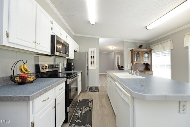 205 N Raleigh Farms Rd, Youngsville, NC 27596 - kitchen with appliances with stainless steel finishes, light wood-style flooring, white cabinets, a center island with sink, and ornamental molding