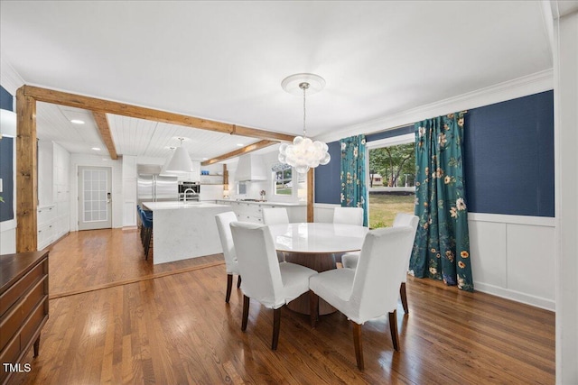 8909 Hunting Trl, Raleigh, NC 27613 - dining space with a chandelier, wood finished floors, beam ceiling, a wainscoted wall, and a decorative wall