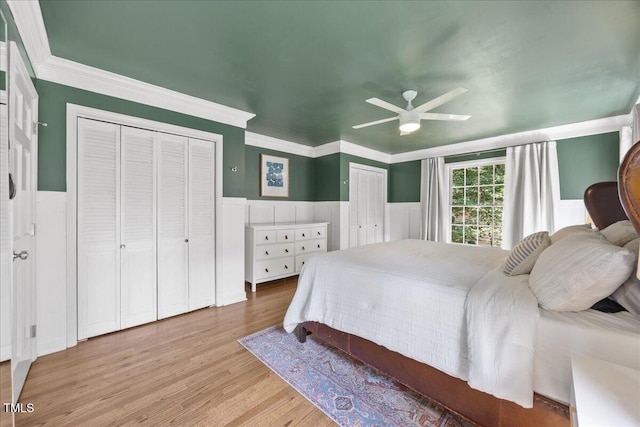 8909 Hunting Trl, Raleigh, NC 27613 - bedroom featuring wainscoting, wood finished floors, multiple closets, ceiling fan, and ornamental molding