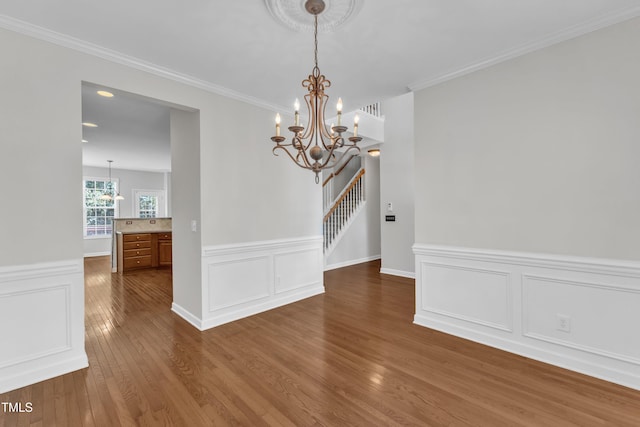 3905 Song Sparrow Dr, Wake Forest, NC 27587 - unfurnished dining area with a chandelier, dark wood-type flooring, a wainscoted wall, crown molding, and stairway