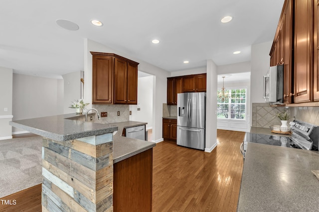 3905 Song Sparrow Dr, Wake Forest, NC 27587 - kitchen with appliances with stainless steel finishes, tasteful backsplash, a peninsula, wood finished floors, and recessed lighting