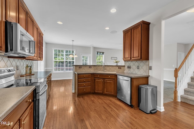 3905 Song Sparrow Dr, Wake Forest, NC 27587 - kitchen with appliances with stainless steel finishes, wood finished floors, brown cabinets, backsplash, and recessed lighting