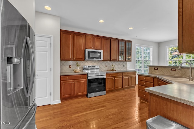 3905 Song Sparrow Dr, Wake Forest, NC 27587 - kitchen featuring stainless steel appliances, light wood-type flooring, backsplash, brown cabinets, and recessed lighting