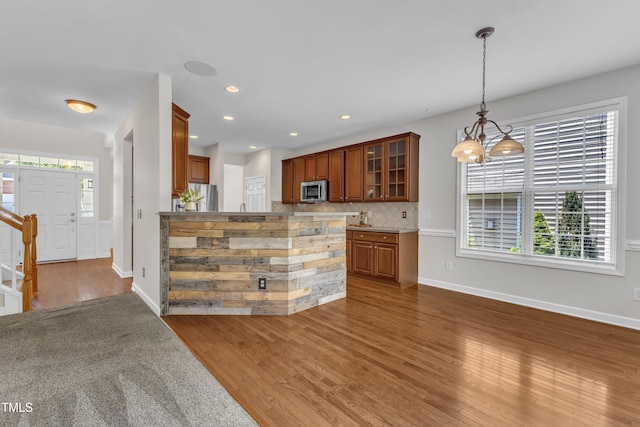 3905 Song Sparrow Dr, Wake Forest, NC 27587 - kitchen featuring stainless steel appliances, a chandelier, wood finished floors, backsplash, and glass insert cabinets