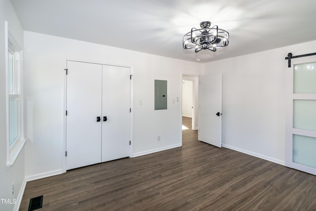 5920 Holly Dr, Raleigh, NC 27616 - unfurnished bedroom featuring dark wood-type flooring, electric panel, a barn door, a chandelier, and a closet