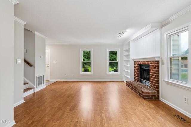 3405 E Jameson Rd, Raleigh, NC 27604 - unfurnished living room with built in shelves, wood finished floors, stairs, a fireplace, and crown molding