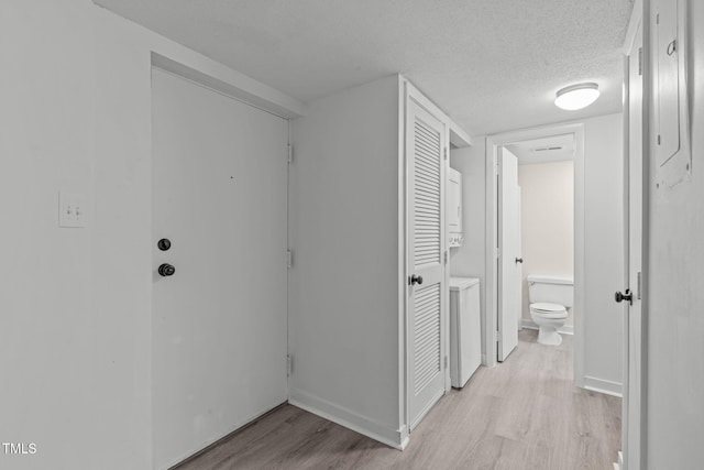 624 Pine Ridge Pl, Raleigh, NC 27609 - corridor featuring estacked washer and dryer, light wood-type flooring, and a textured ceiling