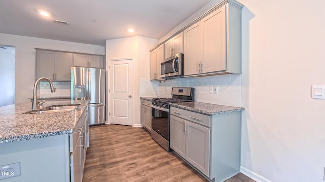 67 Red Cedar Way, Fuquay Varina, NC 27526 - kitchen with appliances with stainless steel finishes, wood finished floors, backsplash, stone counters, and gray cabinetry