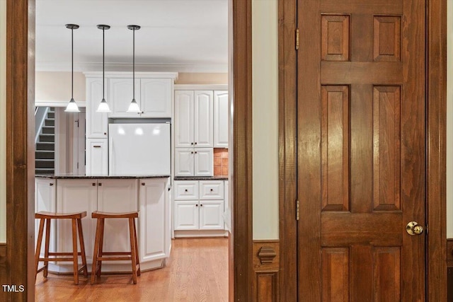 12329 Whartons Way, Raleigh, NC 27613 - kitchen featuring fridge, white cabinets, light wood-style flooring, a kitchen bar, and decorative light fixtures
