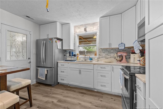 3374 Legion Rd, Hope Mills, NC 28348 - kitchen with stainless steel appliances, white cabinets, light countertops, and a textured ceiling
