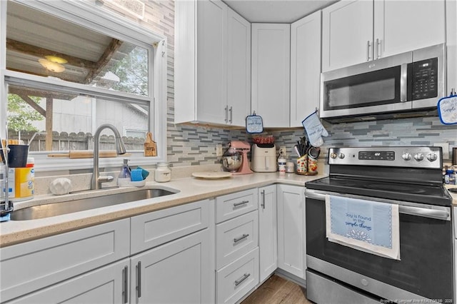 3374 Legion Rd, Hope Mills, NC 28348 - kitchen featuring stainless steel appliances, white cabinetry, tasteful backsplash, and wood finished floors
