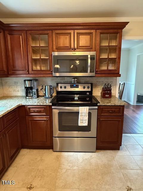 138 Dorsey Pl, Henderson, NC 27536 - kitchen featuring appliances with stainless steel finishes, decorative backsplash, light stone countertops, and glass insert cabinets