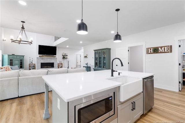412 Stable Ct, Linden, NC 28356 - kitchen with appliances with stainless steel finishes, a lit fireplace, light wood-style flooring, light countertops, and decorative light fixtures