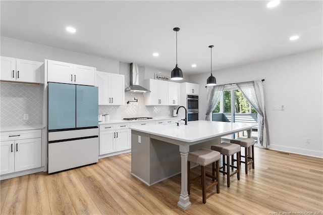 412 Stable Ct, Linden, NC 28356 - kitchen featuring stainless steel appliances, wall chimney range hood, light countertops, light wood-style floors, and backsplash