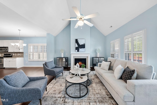 308 Minton Valley Ln, Cary, NC 27519 - living room with a chandelier, dark wood finished floors, ceiling fan, a lit fireplace, and high vaulted ceiling