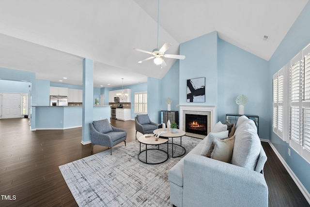 308 Minton Valley Ln, Cary, NC 27519 - living room featuring a glass covered fireplace, dark wood-type flooring, a ceiling fan, high vaulted ceiling, and a chandelier