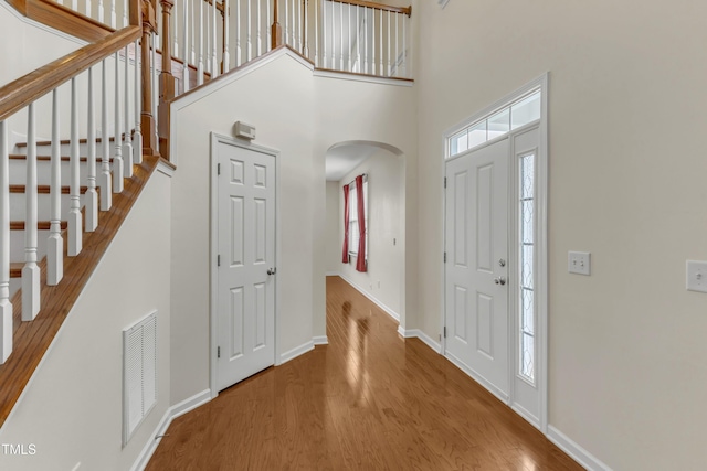 2801 Casona Way, Raleigh, NC 27616 - foyer featuring arched walkways, wood finished floors, a high ceiling, and stairs