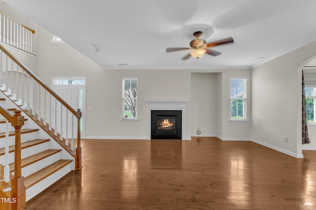 2801 Casona Way, Raleigh, NC 27616 - unfurnished living room featuring ceiling fan, arched walkways, a glass covered fireplace, wood finished floors, and stairs