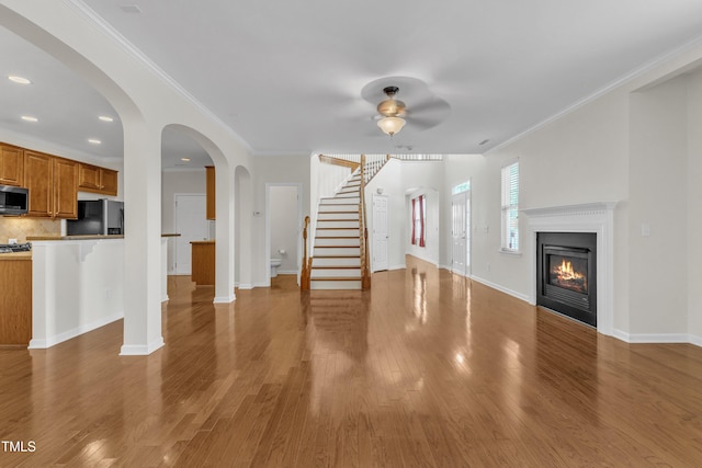 2801 Casona Way, Raleigh, NC 27616 - unfurnished living room with ceiling fan, wood finished floors, a glass covered fireplace, stairs, and ornamental molding