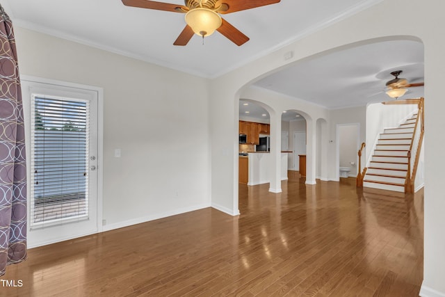 2801 Casona Way, Raleigh, NC 27616 - unfurnished living room featuring ceiling fan, wood finished floors, stairs, arched walkways, and crown molding