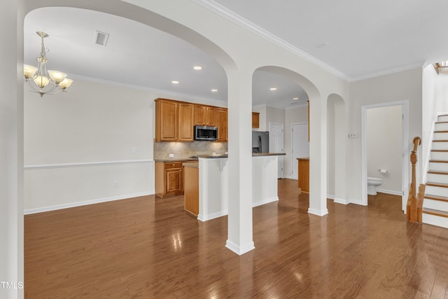 2801 Casona Way, Raleigh, NC 27616 - kitchen with stainless steel microwave, decorative backsplash, brown cabinets, dark wood-style flooring, and crown molding
