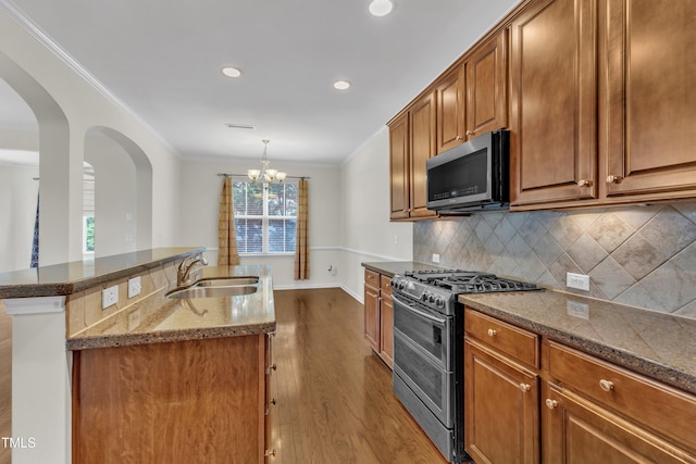 2801 Casona Way, Raleigh, NC 27616 - kitchen featuring appliances with stainless steel finishes, crown molding, dark stone counters, arched walkways, and dark wood-style floors