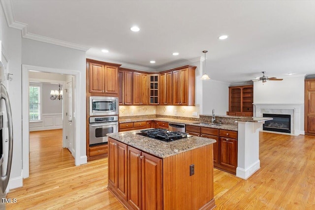 5001 Sears Farm Rd, Cary, NC 27519 - kitchen featuring stainless steel appliances, a glass covered fireplace, brown cabinetry, a peninsula, and ornamental molding