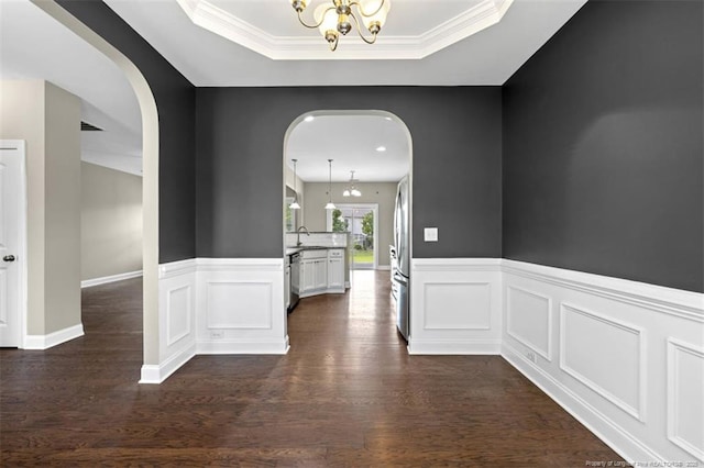 17 Tanawha Ct, Spring Lake, NC 28390 - hallway featuring arched walkways, a chandelier, wainscoting, dark wood-style floors, and a tray ceiling