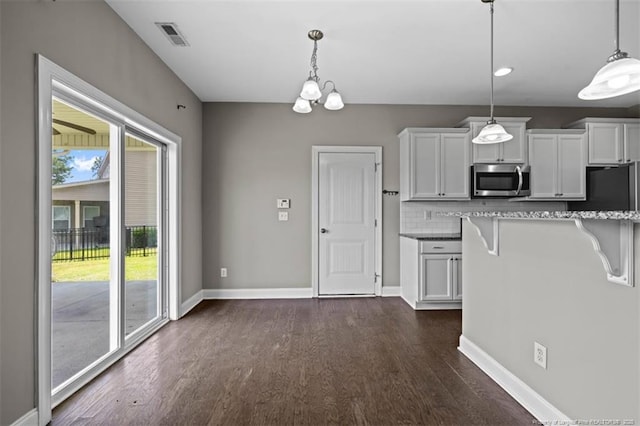 17 Tanawha Ct, Spring Lake, NC 28390 - kitchen featuring stainless steel microwave, dark wood-type flooring, fridge, a breakfast bar, and decorative light fixtures