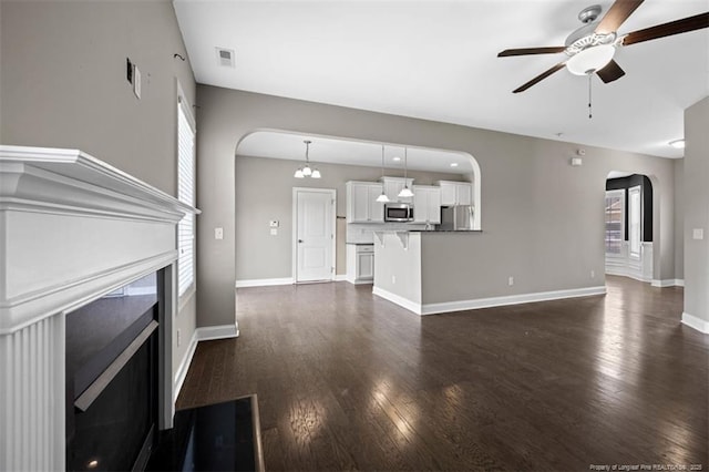 17 Tanawha Ct, Spring Lake, NC 28390 - unfurnished living room with arched walkways, a ceiling fan, dark wood-type flooring, and a fireplace