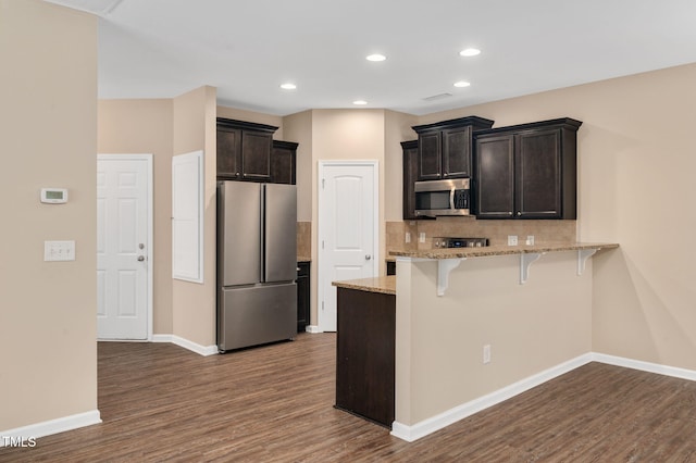 516 Smithridge Way, Fuquay Varina, NC 27526 - kitchen with stainless steel appliances, dark wood finished floors, a breakfast bar area, a peninsula, and backsplash