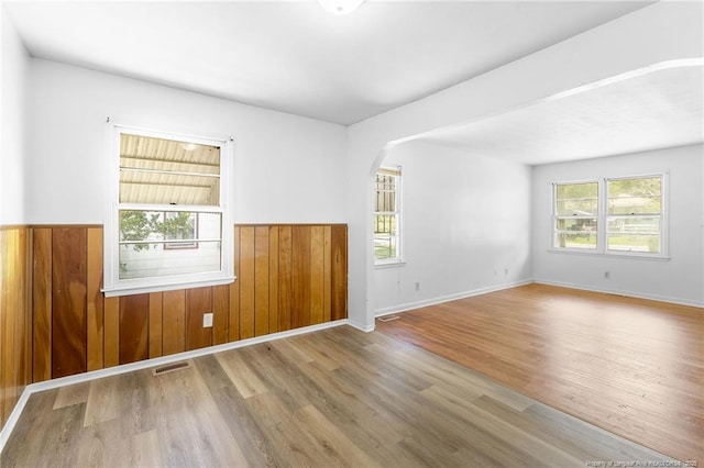 1109 Chesterfield Dr, Fayetteville, NC 28305 - empty room featuring wood finished floors, arched walkways, a wainscoted wall, and wood walls