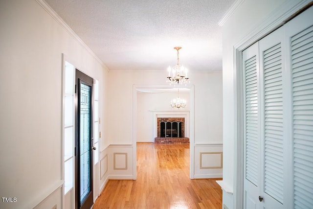 70 Sand Trap Ln, Roxboro, NC 27574 - hall with ornamental molding, a chandelier, light wood-style floors, a textured ceiling, and wainscoting